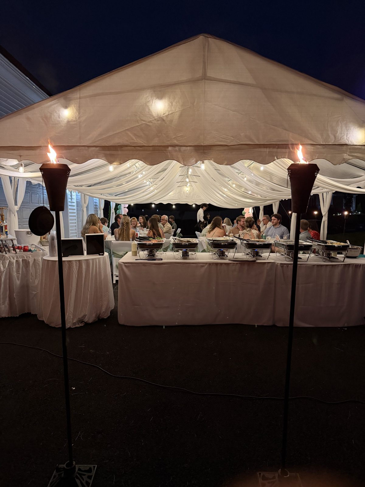 Tent lit up at night with tiki torches